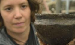 Member of Cambridge Archaeological Unit holding pot