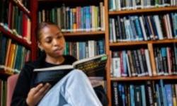 Young woman reading in front of library shelves