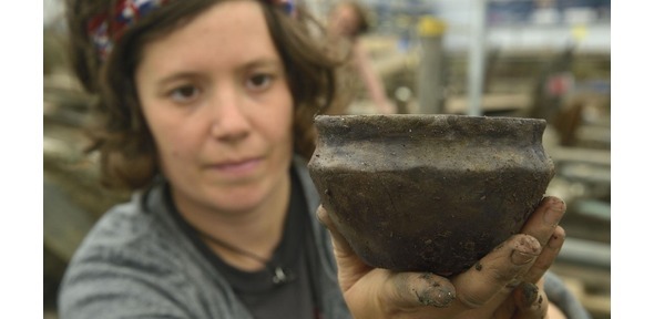 Member of Cambridge Archaeological Unit holding pot
